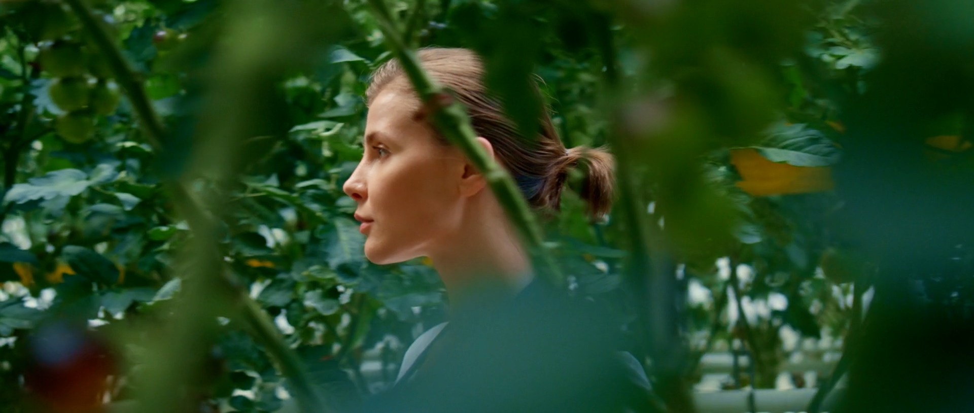 Woman looking through lush green foliage